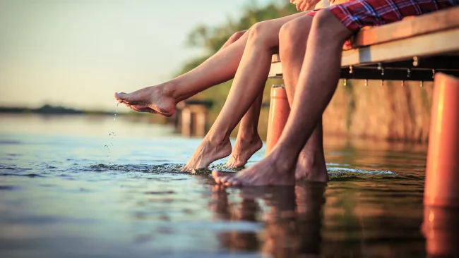 Beine baumeln von einem Steg in einen See